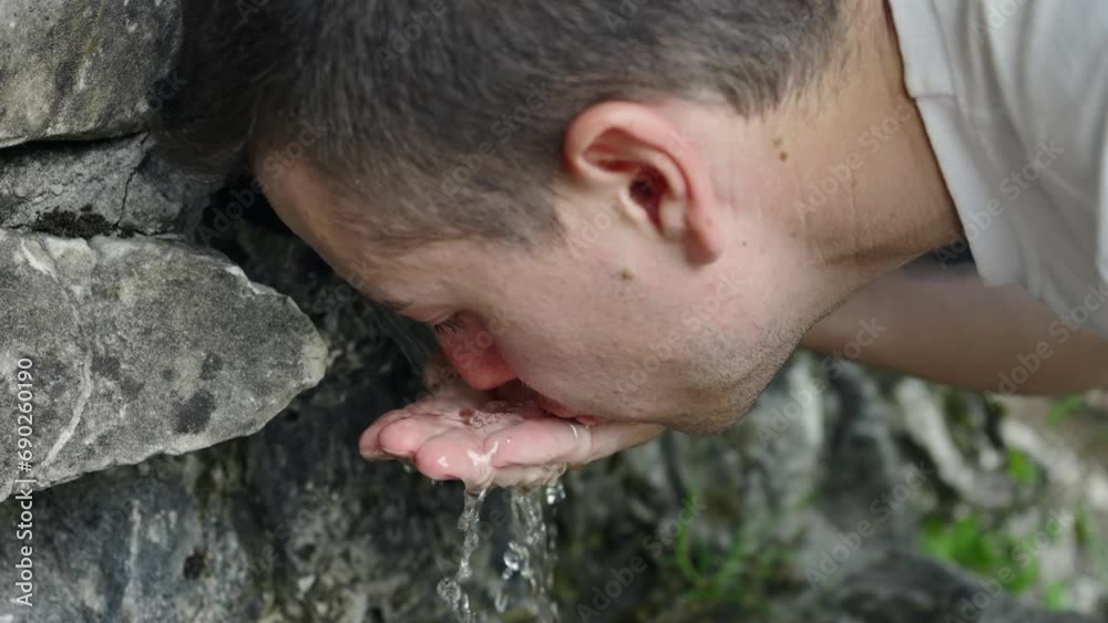 Hiker men drinking water. Making a sip of mountain river water from the palms of his hands from the mountain creek. when hiking, slow motion Hiker men drinking water. Making a sip of mountain river water from the palms of his hands from the mountain creek. when hiking, slow motion