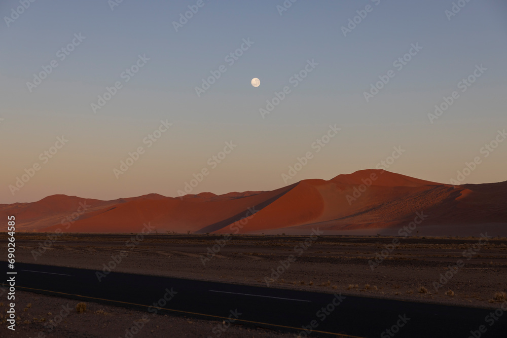 As the dawn begins to break over the Namibian dunes the Moon begins to set