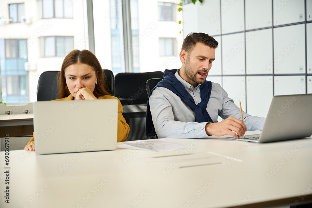 Upset colleagues are sitting at their workplaces Upset colleagues are sitting at their workplaces