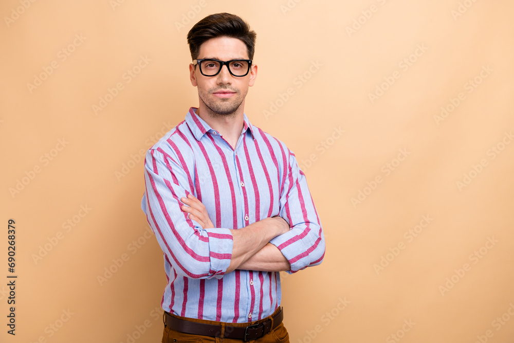 Portrait of young confident handsome brunet hair entrepreneur man wear elegant striped shirt folded arms isolated on beige color background