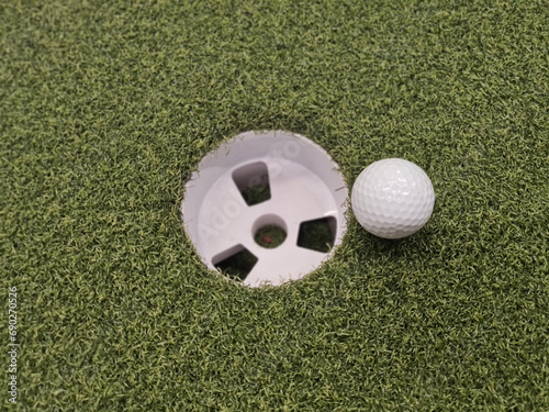 Golf ball and golf hole on green lawn concept