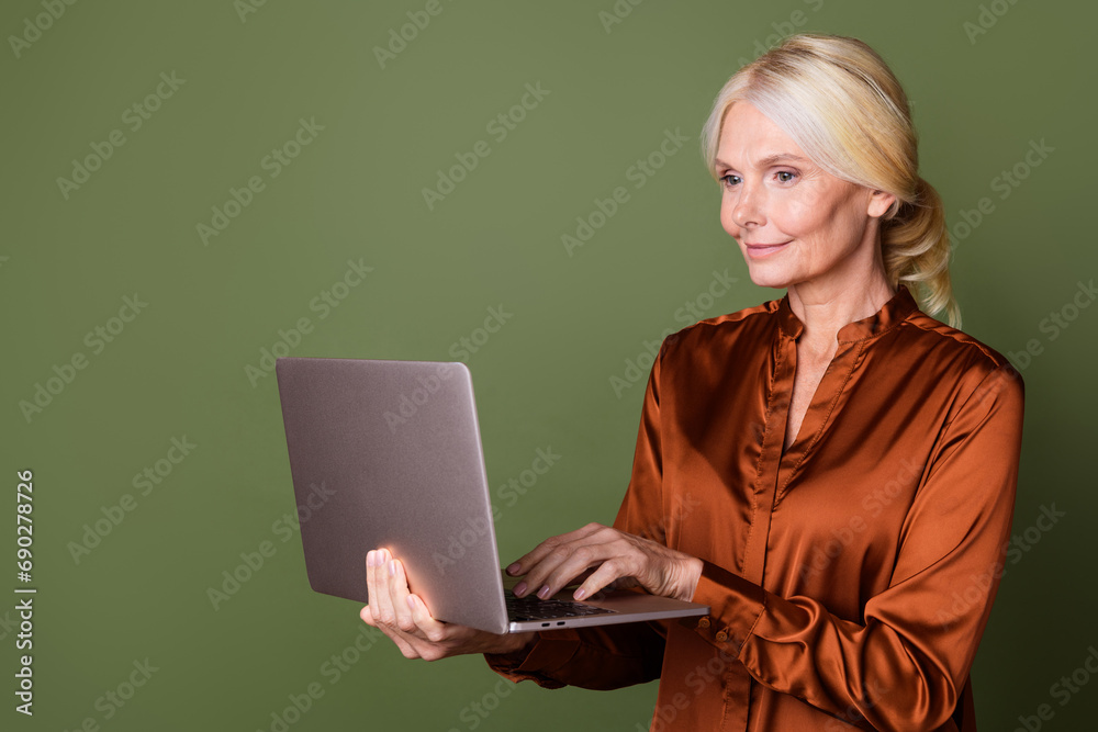 Photo portrait of pretty retired female hold netbook working dressed stylish brown silk outfit isolated on khaki color background Photo portrait of pretty retired female hold netbook working dressed stylish brown silk outfit isolated on khaki color background
