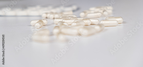 A lot of white capsules are scattered on the table. Drug concept, pharmacy. Place for text