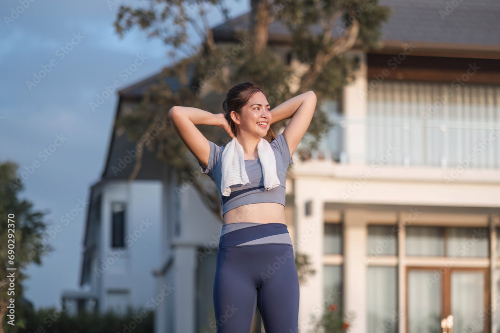 Young Asian woman exercising before a fitness session at the park in front of her house. Young healthy woman warming up outdoors She was stretching her arms and looking away.