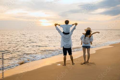 Father carrying son and Mother carrying daughter on shoulder walking summer beach, Parents carrying children on shoulders at beach on sunset, Family on holiday summer vacation, Happy family in holiday photo