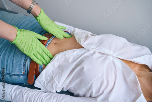 Experienced physician performing abdominal exam of adult person