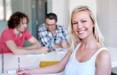 Portrait, happy business woman writing at table in meeting and coworking in office, creative company or workplace. Face, smile and writer on book, employee or person at startup job or career at desk