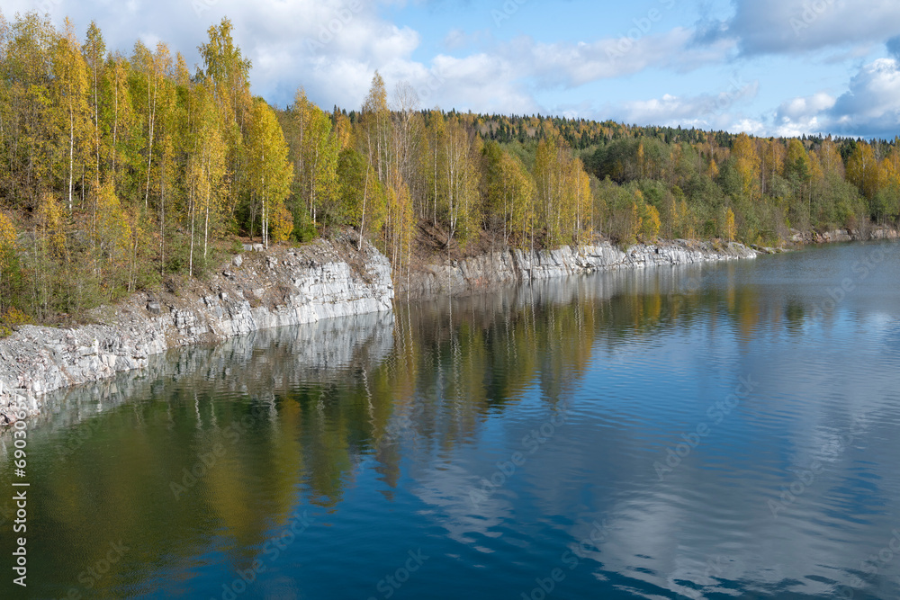 The shore of an old flooded marble quarry in golden autumn. The outskirts of the Ruskeala village. Karelia, Russia