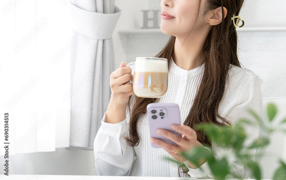 パソコンを使いながら飲み物を飲む女性 パソコンを使いながら飲み物を飲む女性