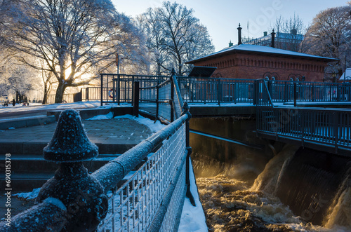 White winter in Sweden, Low winter sun shining on steaming water of  Faunapassage on Svartån river next to the old turbine house in Västerås city