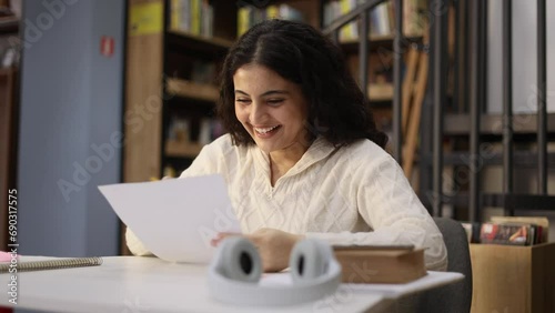 Portrait of happy student got an excellent grade mark for the test at university class Cute curly smiling girl looking at test in good mood indoors Exam passed Successful education concept photo