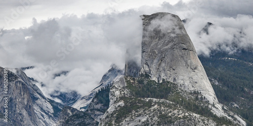 The sheer granite face of Half Dome, shrouded in clouds, on an autumn day in Yosemite National Park in California. photo