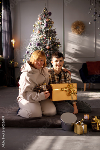Happy boy and girl sitting next to their grandmother with Christmas gifts, near the Christmas tree. New Year's traditions for the whole family