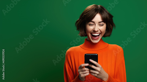 Happy smiling young woman is using her smartphone against green background