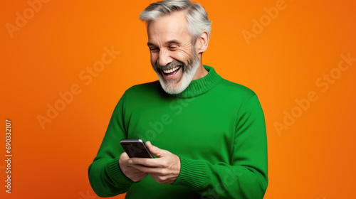 Senior man is using a smartphone against orange background.