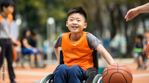 Smiling boy in a wheelchair playing a basketball on an outdoor court. photo