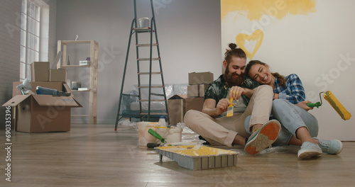 Newlywed caucasian couple is renovating their new home, painting the walls and positively smiling - new life, young family, mortgage concept  photo