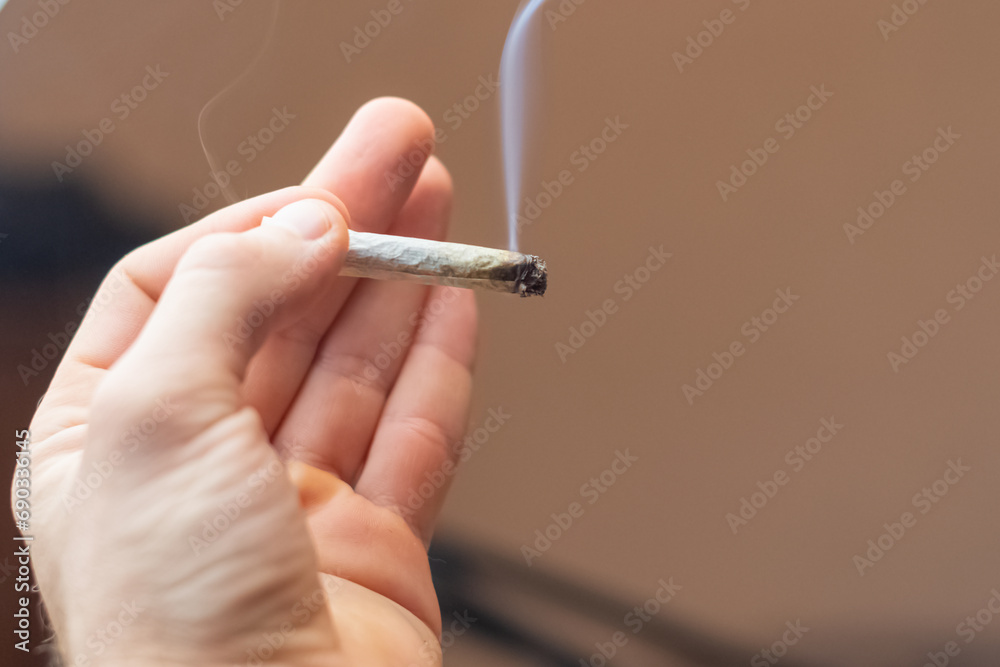 holding in hand smoking canabis joint, selective focus background copy space image holding in hand smoking canabis joint, selective focus background copy space image