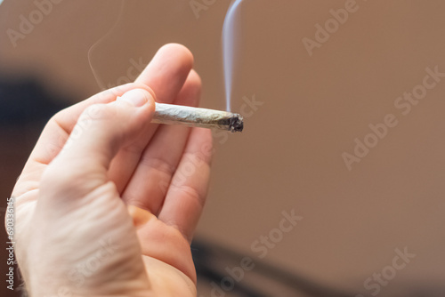 holding in hand smoking canabis joint  selective focus background copy space image