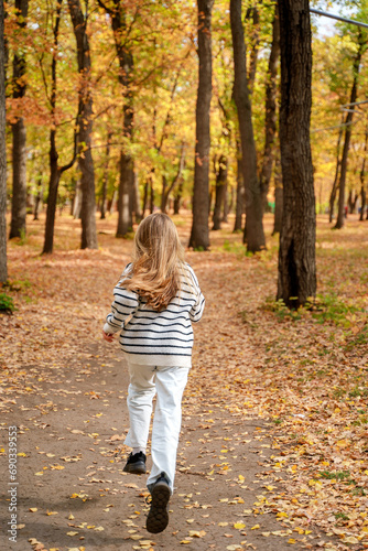 A beautiful teenage girl with long hair smiles and runs in an autumn park. Togliatti, Russia - 30 Sep 2023