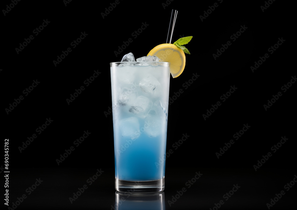 A Blue Curacao Lemonade, its vivid blue color captivating against the black surface, placed centrally for a dramatic effect. A Blue Curacao Lemonade, its vivid blue color captivating against the black surface, placed centrally for a dramatic effect.