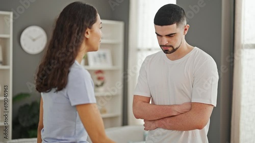 Serious argument at home, a beautiful couple locked in disagreement, standing together in their living room showcasing a lifestyle conflict. photo