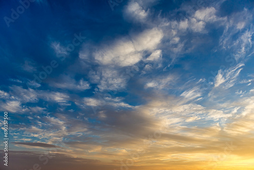 Cumulostratus, Stratus and Altocumulus clouds at golden hour in the blue sky lit by the sun at sunset or sunrise. Morning or evening, winter or summer. Blue and yellow gradient in the sky.