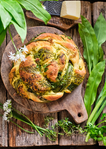 Bread with herbs. Bread braid with wild garlic, chives and pesto. Top view, wooden background.