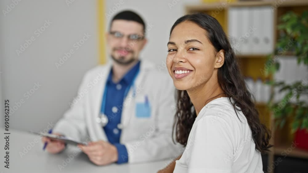 Smiling doctor and patient confidently discussing medical report together at clinic Smiling doctor and patient confidently discussing medical report together at clinic