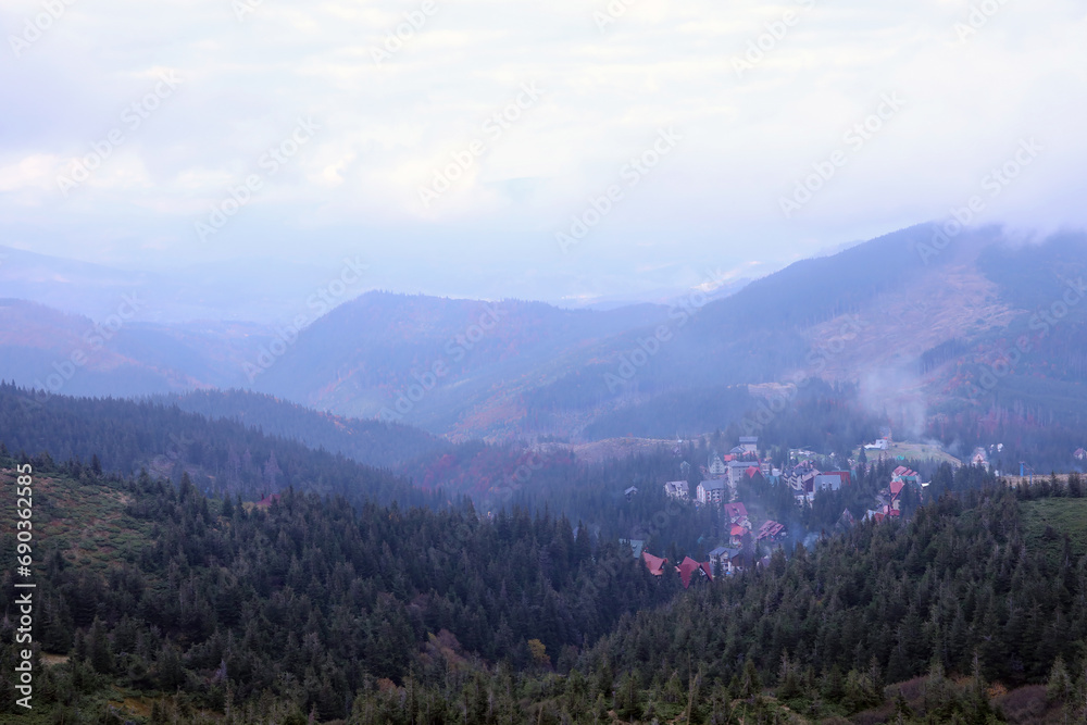 Morning view of residental area and houses around the Dragobrat mountain peaks in Carpathian mountains, Ukraine. Cloudy and foggy landscape around Drahobrat Peaks in early morning Morning view of residental area and houses around the Dragobrat mountain peaks in Carpathian mountains, Ukraine. Cloudy and foggy landscape around Drahobrat Peaks in early morning