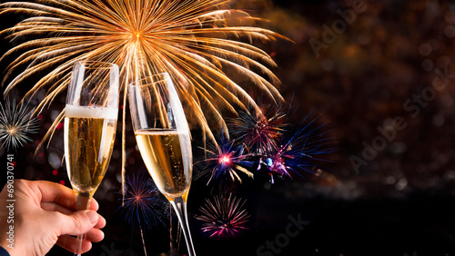 Brinde com taça de champagne e decoração dourada para celebração de ano novo e fogos de artificio ao fundo.