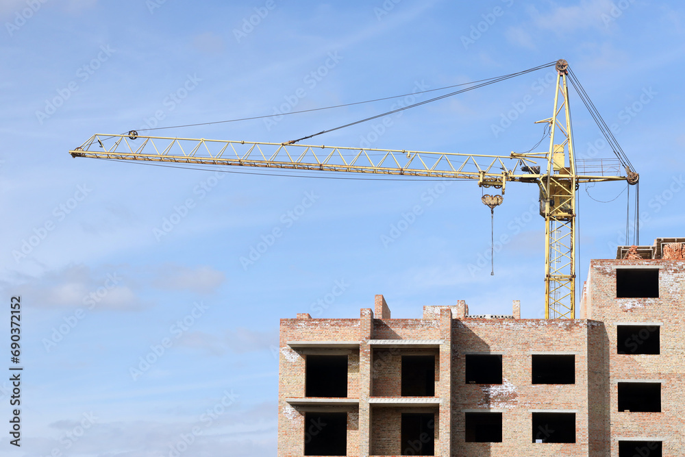 View of a large construction site with buildings under construction and multi-storey residential homes. Tower cranes in action on blue sky background. Housing renovation concept. Crane during View of a large construction site with buildings under construction and multi-storey residential homes. Tower cranes in action on blue sky background. Housing renovation concept. Crane during