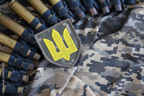 Ukrainian army symbol on machine gun belt lies on ukrainian pixeled military camouflage close up photo