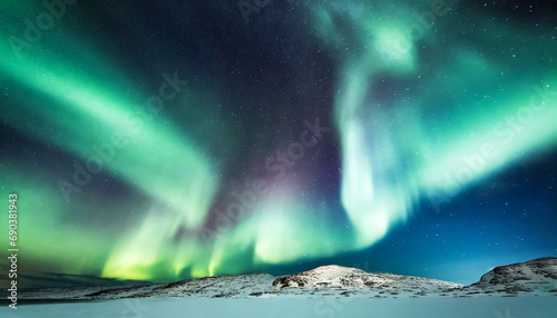 Aurora borealis or northern lights with starry glowing in the night sky and snowed hill. © Karo