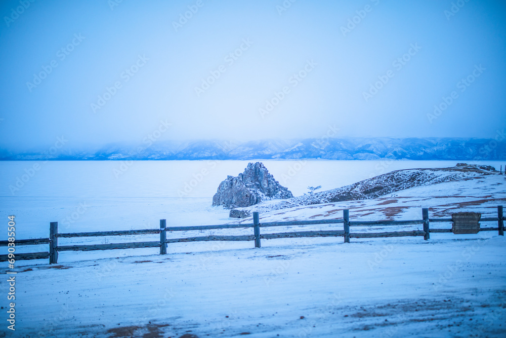 Beautiful winter landscape of snowy rock mountains and frozen Lake Baikal in a gloomy winter day