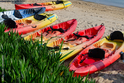 Colored kayaks lie in a row on the beach