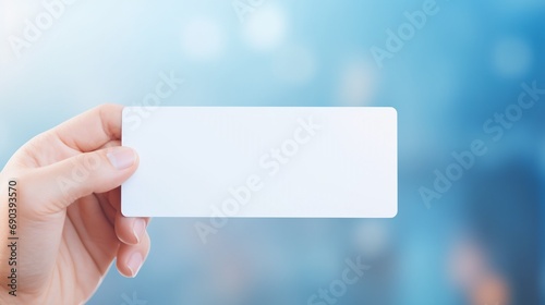 Hand holding white business card on blue blurred background photo