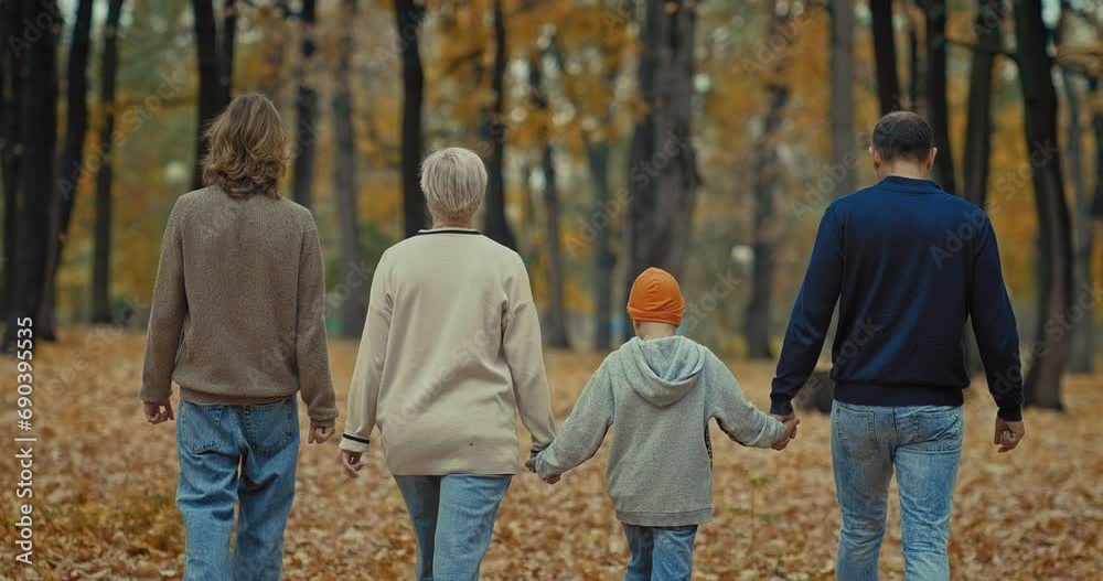 rear view of walking family in beautiful park in autumn, parents and ...