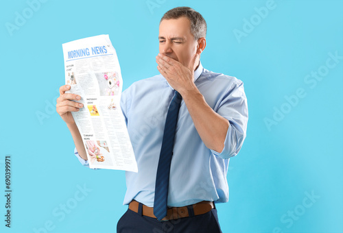 Sleepy mature journalist with newspaper on blue background