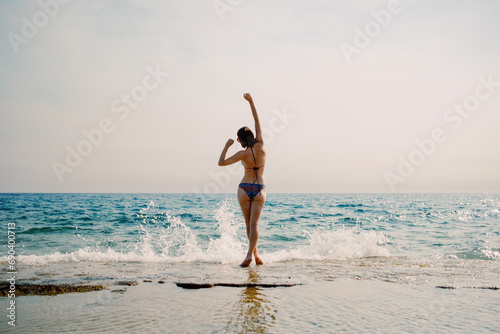 A joyful moment captured as a woman dances on the beach, with the sparkling sea as a perfect backdrop for freedom and happines