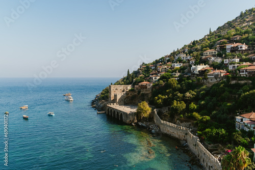 An ancient fortress stands guard beside serene seaside homes, nestled above the tranquil blue waters of the Mediterranean