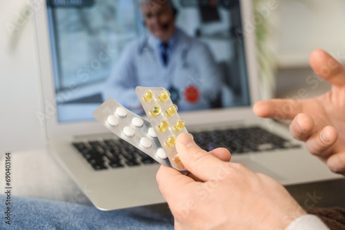 Ill young man with pills video chatting at home, closeup