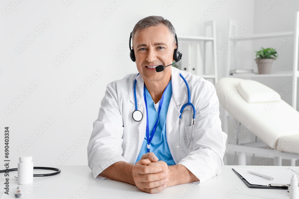 Mature doctor in headset video chatting at hospital