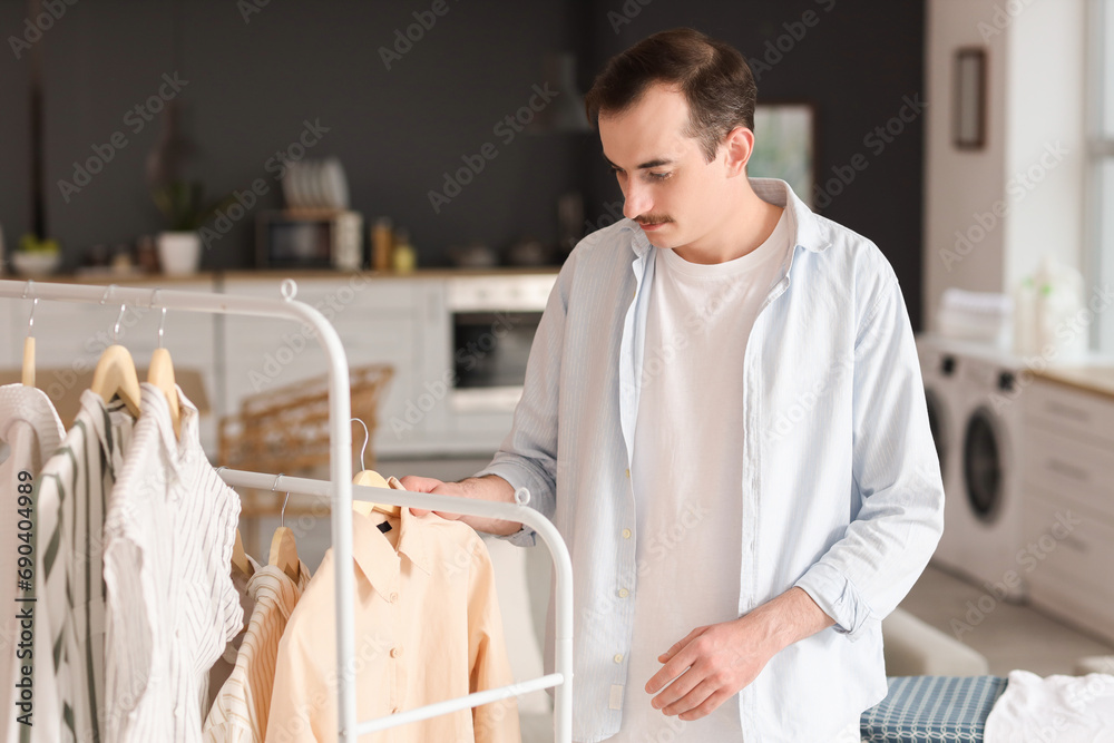 Young man hanging ironed laundry on rack in kitchen Young man hanging ironed laundry on rack in kitchen