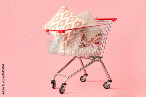 Shopping cart with cushions on pink background