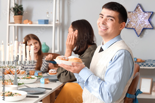 Young man with donuts having family dinner at home on Hanukkah
