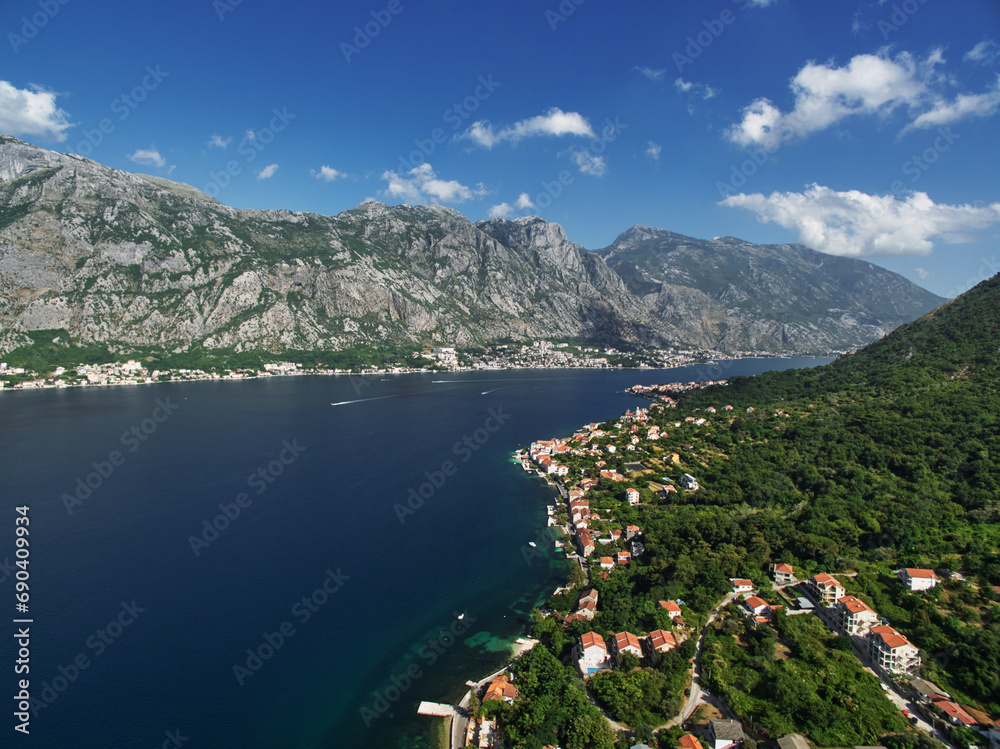 Resort town on the shores of the Bay of Kotor among green trees at the foot of the mountains. Montenegro. Drone