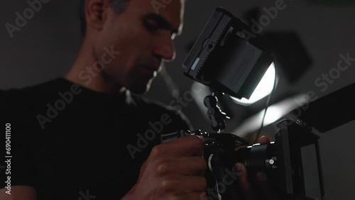 Close-up male filmmaker holding camera. Video production backstage. Professional camera man creating video content in studio, commercial filming.
 photo