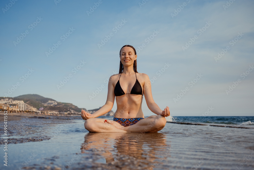 Woman in meditation, the sunset casting a warm glow on the beach