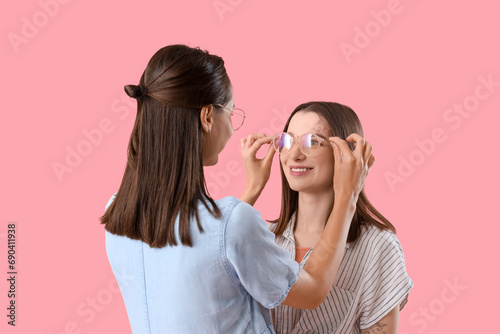 Young women in eyeglasses on pink background